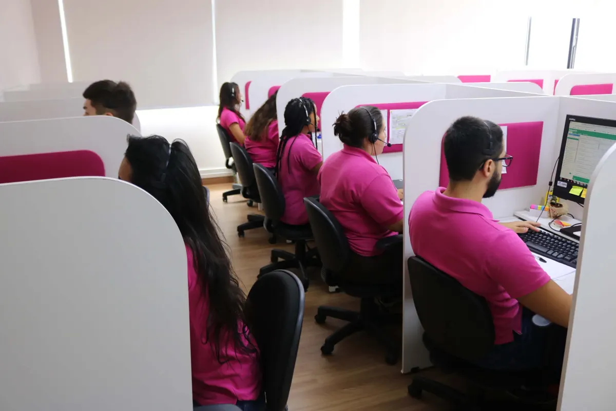 Sala de atendimento com atendentes de SAC usando headset