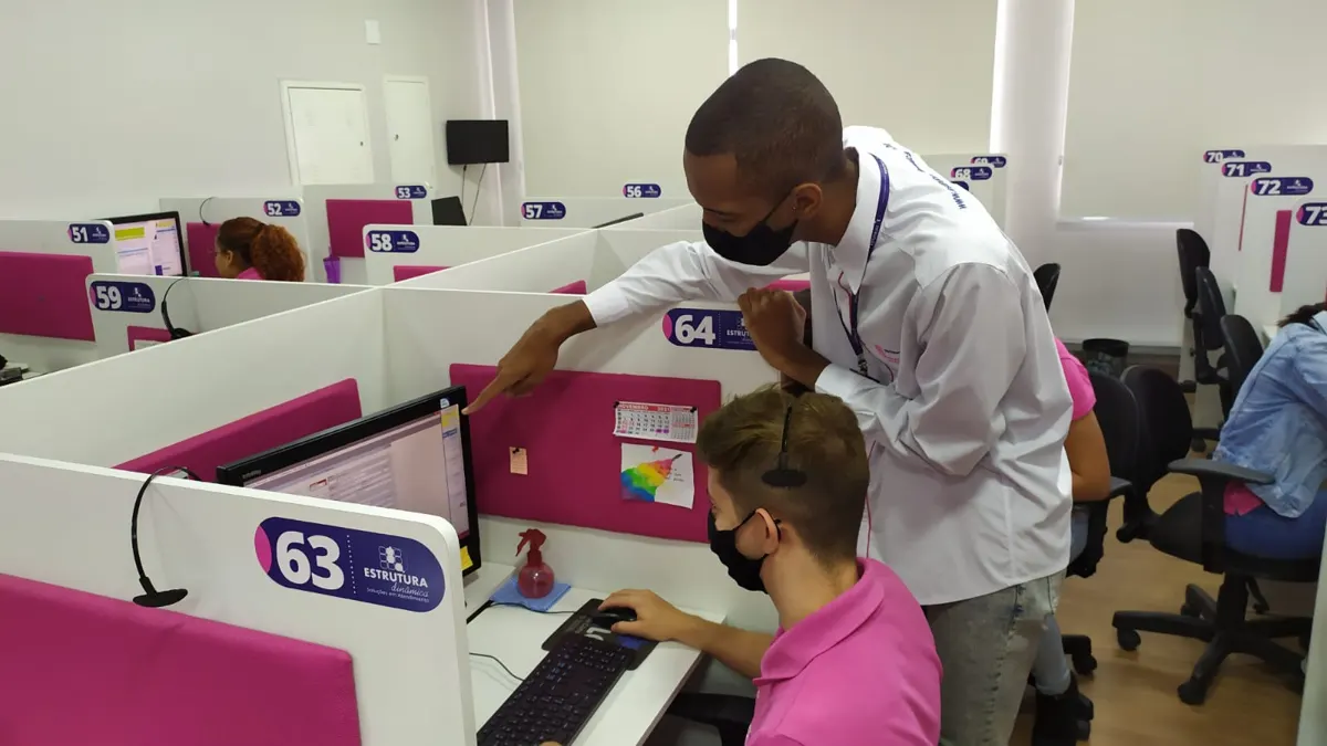 Supervisor ajudando uma atendente de SAC na posição de atendimento